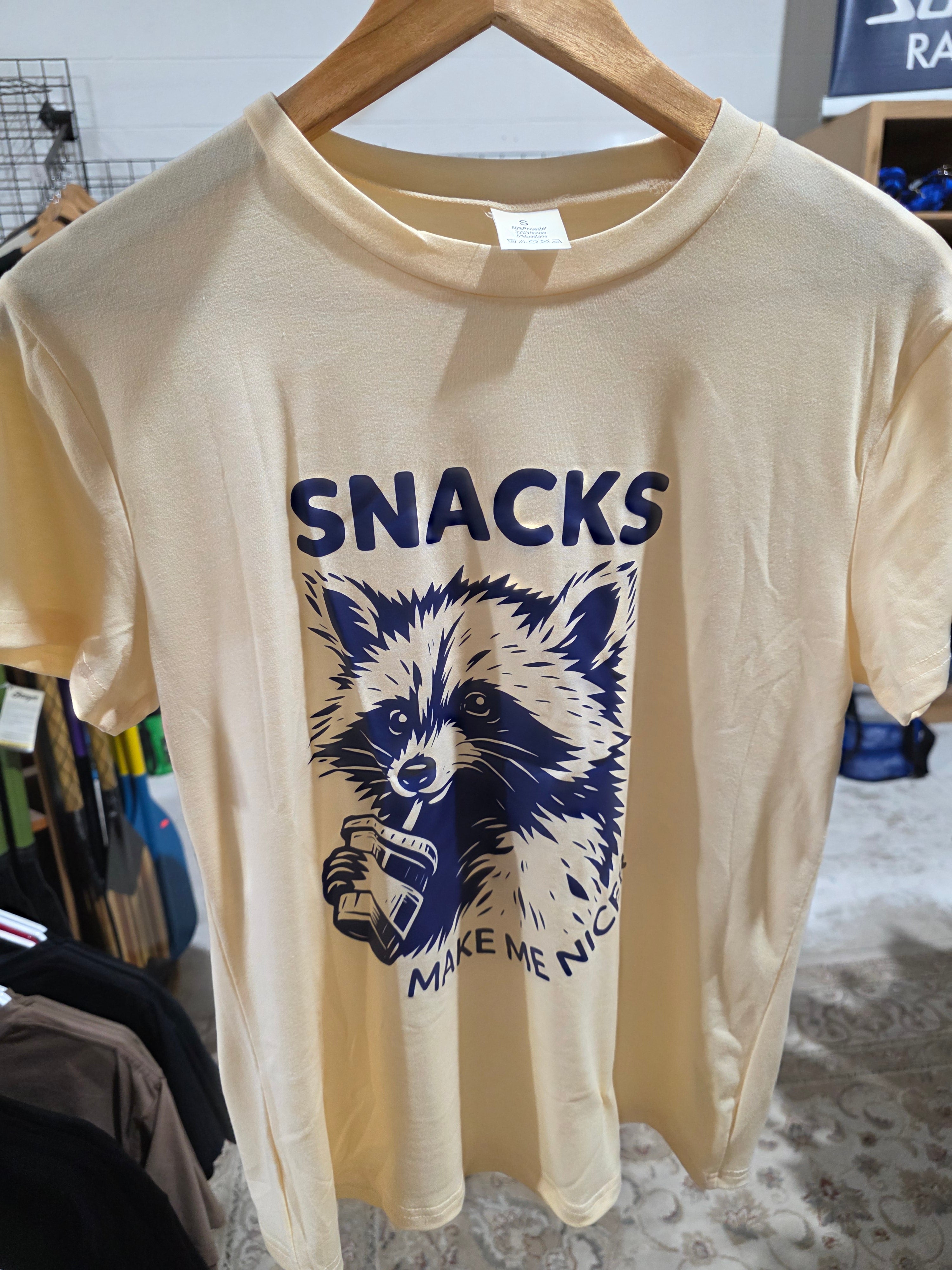Beige t-shirt with a graphic of a wolf and the word 'SNACKS' on a hanger.