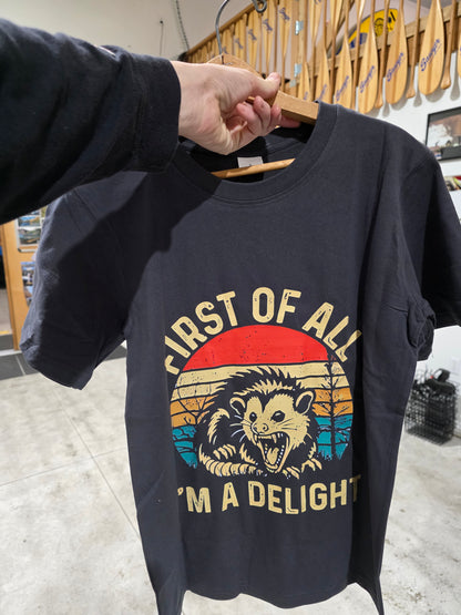 Black t-shirt with graphic design and text held by a person in a store setting