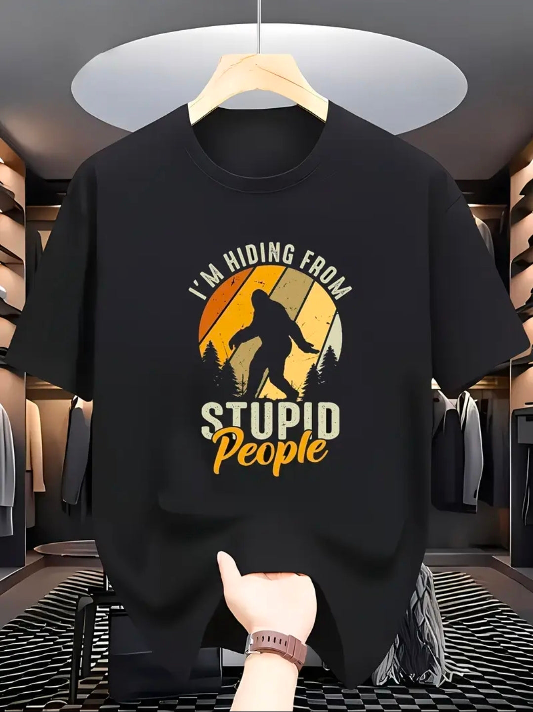 Black t-shirt with graphic design and text held up in a store.