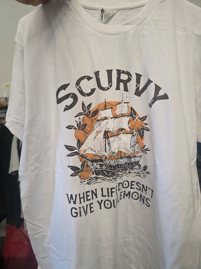 A white short-sleeve graphic t-shirt featuring a vintage-style print of a sailing ship surrounded by oranges and the text 'SCURVY WHEN LIFE DOESN'T GIVE YOU Lemons'.